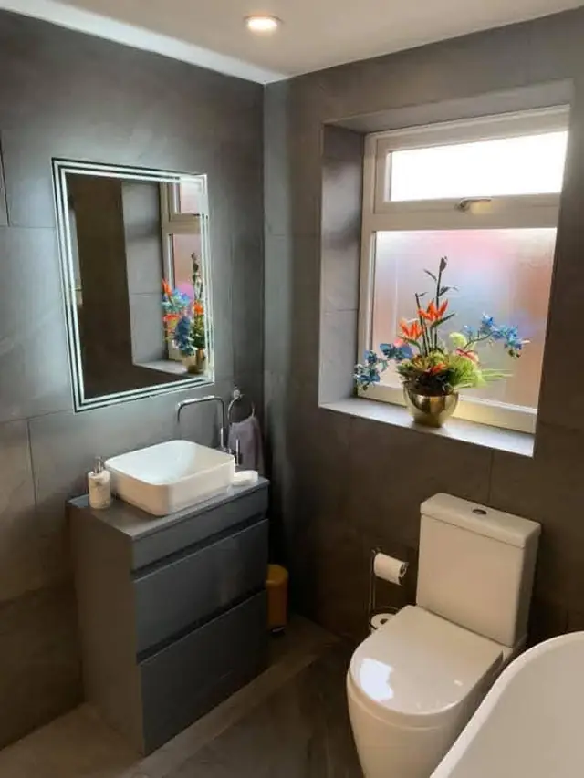 After: a vanity unit with a countertop basin under an LED mirror, next to the toilet.