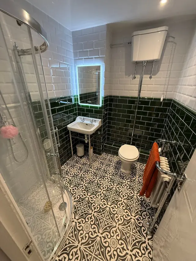 After: the quadrant shower next to the washstand basin and the lit LED mirror.