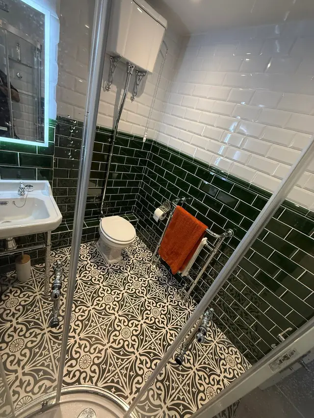 After: green and white metro tiles, a towel radiator and a high-level cistern toilet.