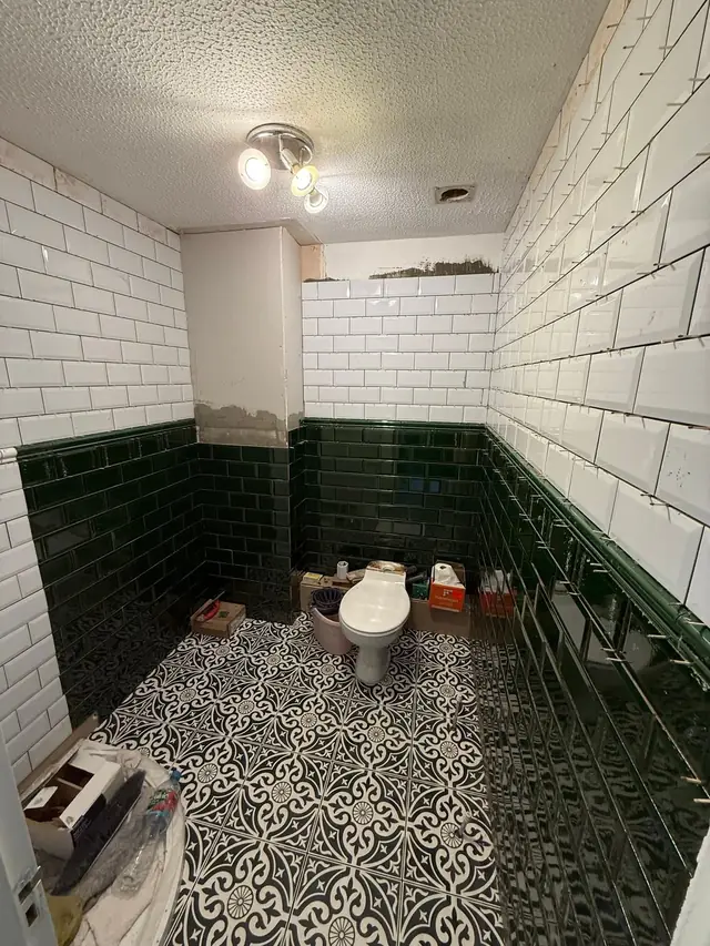 During: green and white metro tiles going up, with the patterned floor tiles laid.