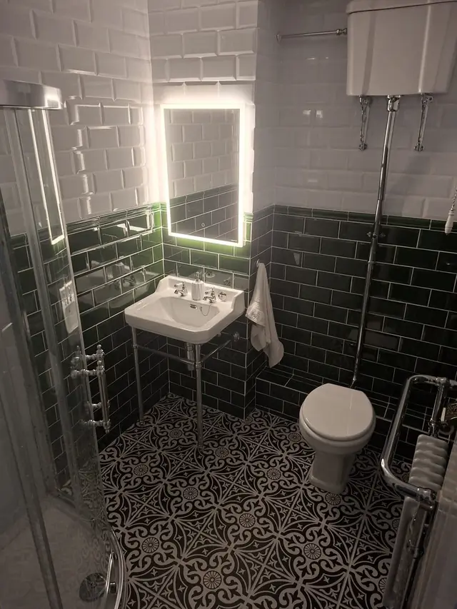 After: the washstand basin under the lit LED mirror, next to the high-level cistern toilet.
