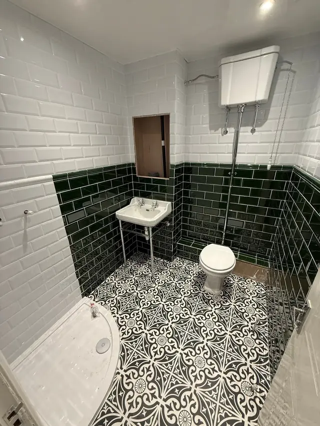During: the shower tray, washstand basin and high-level cistern toilet in place, with the tiling done.