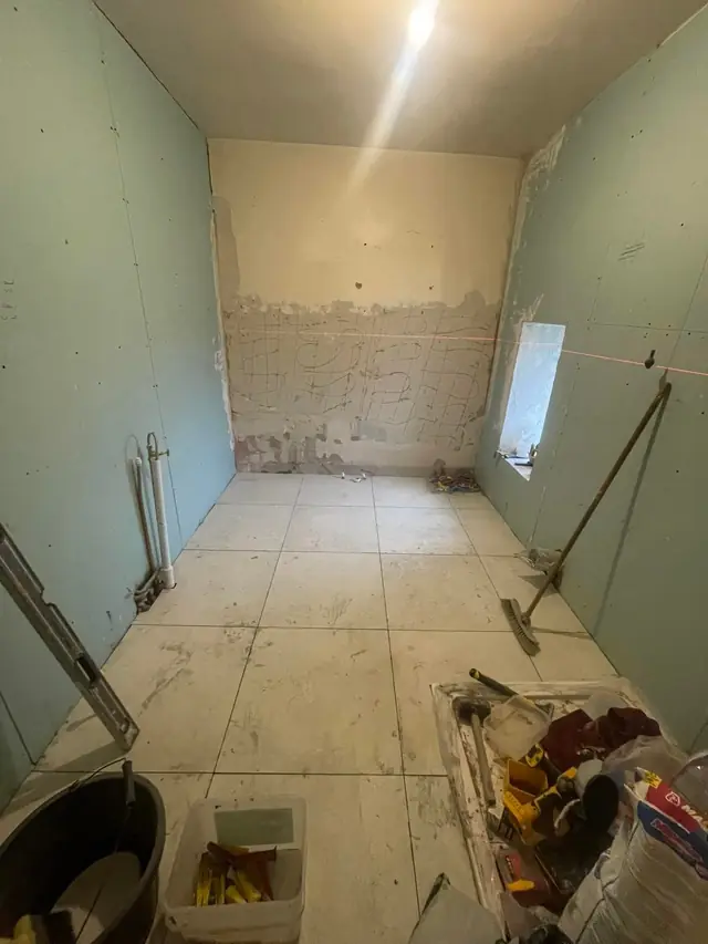 During: the floor tiled and new boards on the walls, ready for tiling.