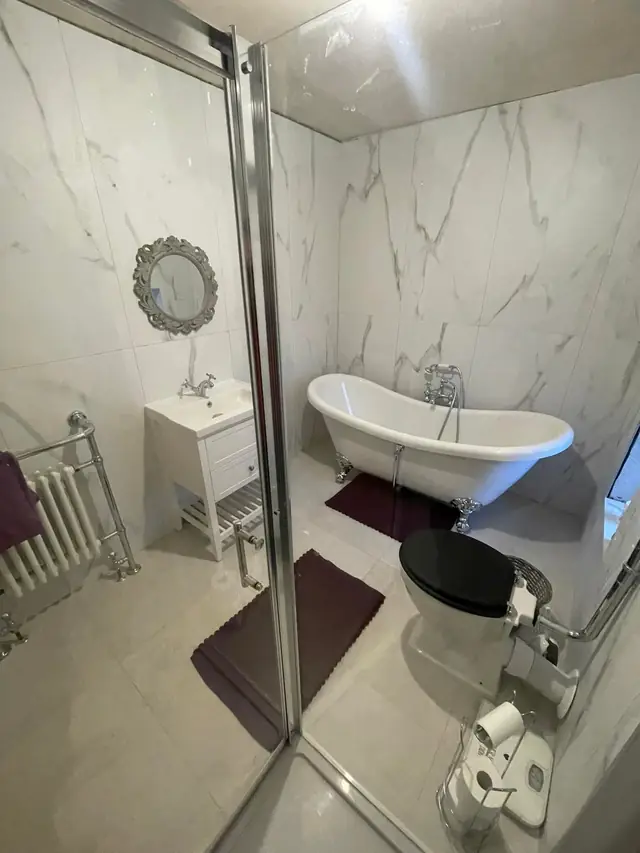 After: the vanity unit and the roll-top bath, with a round mirror on the wall.