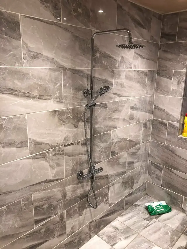 After: the rainfall shower and handset on the tiled wall.